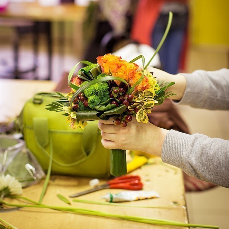 Apprentie fleuriste de l'École des Métiers prépare un bouquet rond