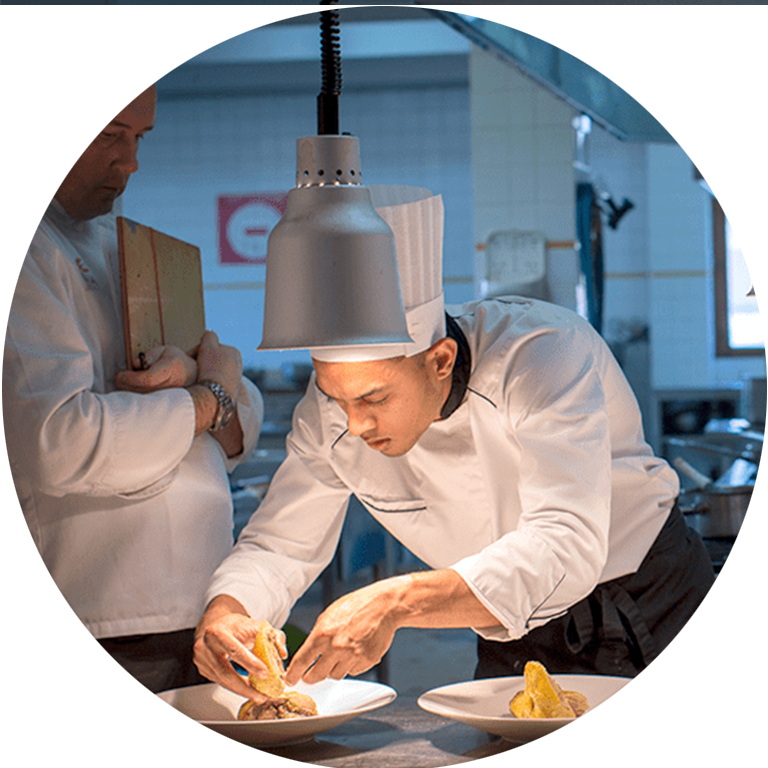 Apprenti cuisinier dresse une assiette à l'École des Métiers Dijon Métropole