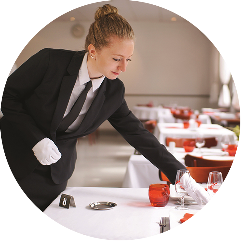 Une apprentie en CAP Commercialisation et services en hôtel-café-restaurant prépare une table à l'EDM.