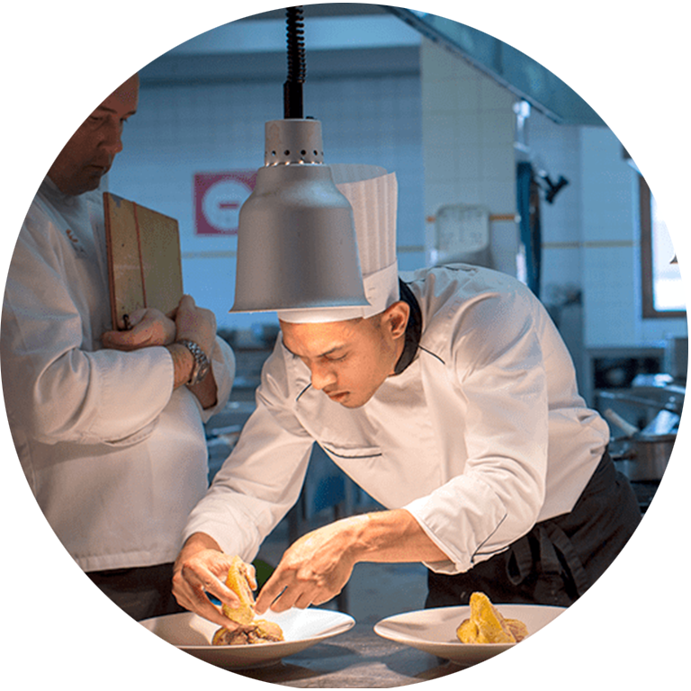 Apprenti cuisinier dresse une assiette à l'École des Métiers Dijon Métropole