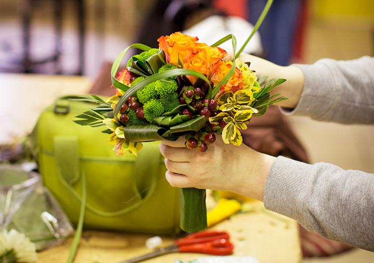 Apprentie fleuriste de l'École des Métiers prépare un bouquet rond